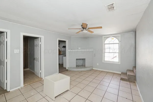a view of an empty room with window and chandelier fan