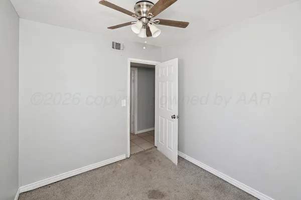 an empty room with windows and fan