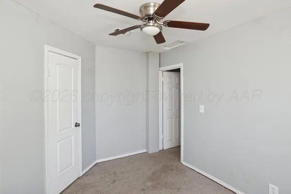 an empty room with windows and fan