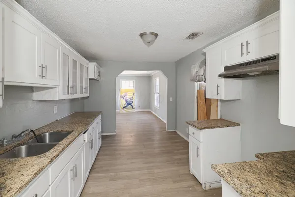 a kitchen with granite countertop a sink stainless steel appliances and cabinets