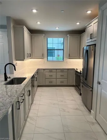 a large kitchen with granite countertop a sink and cabinets