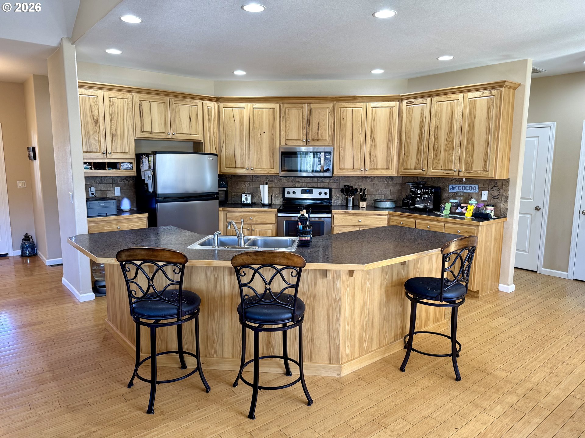 1105 G Street Baker City, OR 97814 - Photo 7 of 33 a kitchen with stainless steel appliances kitchen island granite countertop a refrigerator a stove a sink a dining table and chairs with wooden floor
