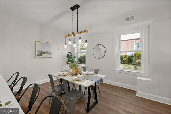 a kitchen with stainless steel appliances granite countertop a sink a stove top oven a dining table and chairs with wooden floor