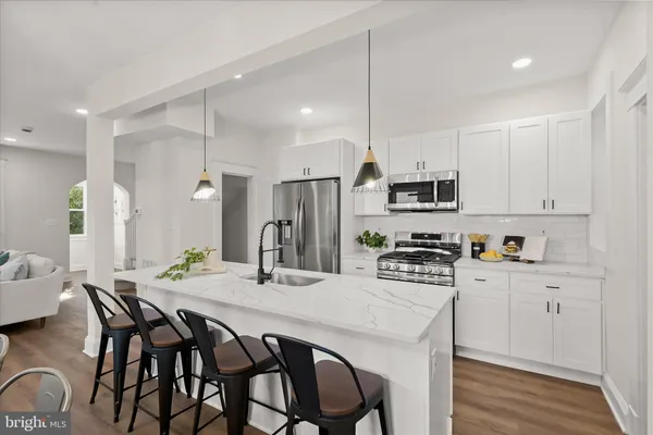 a kitchen with stainless steel appliances kitchen island granite countertop a dining table chairs sink and cabinets