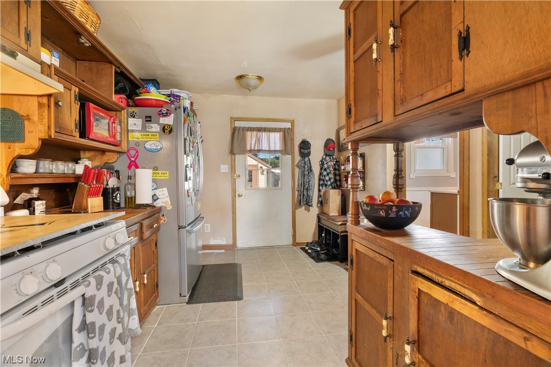 4815 Ridge Avenue Southeast Canton, OH 44707 - Photo 11 of 28 Kitchen with plenty of natural light, brown cabinets, light countertops, white range, and light tile floors