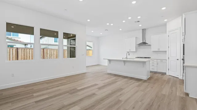 a large kitchen with stainless steel appliances kitchen island wooden floors and view living room
