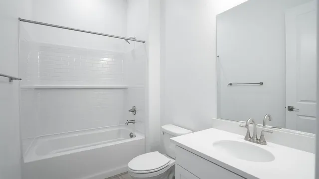 a bathroom with a bathtub shower sink vanity mirror and toilet