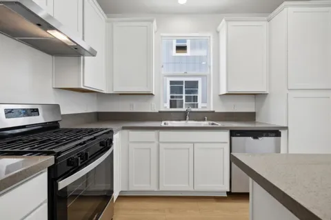 a kitchen with stainless steel appliances granite countertop a sink stove and cabinets