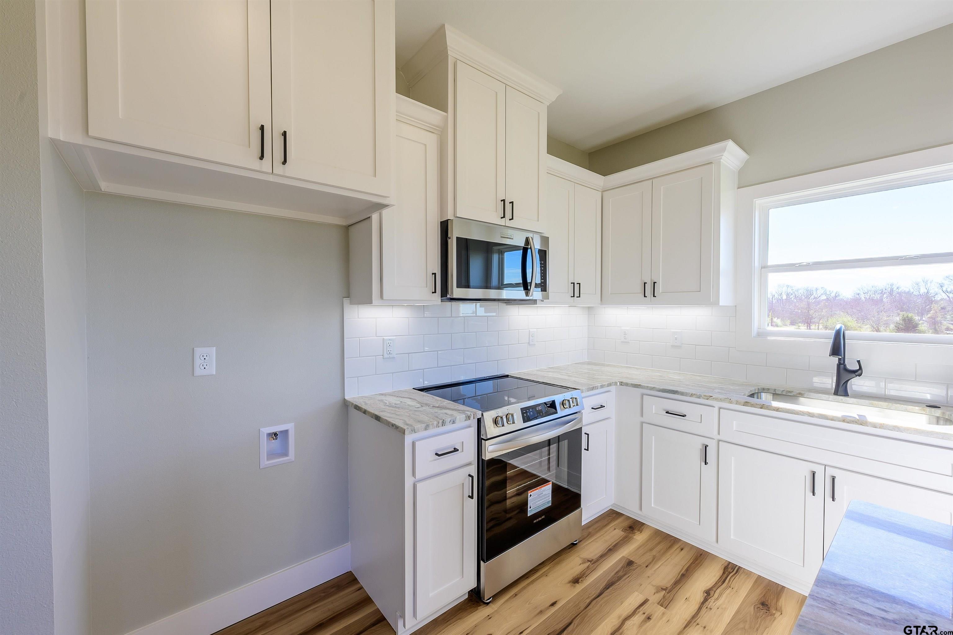 148 Crescent Bullard, TX 75757 - Photo 12 of 40 a kitchen with granite countertop a stove a sink and a microwave