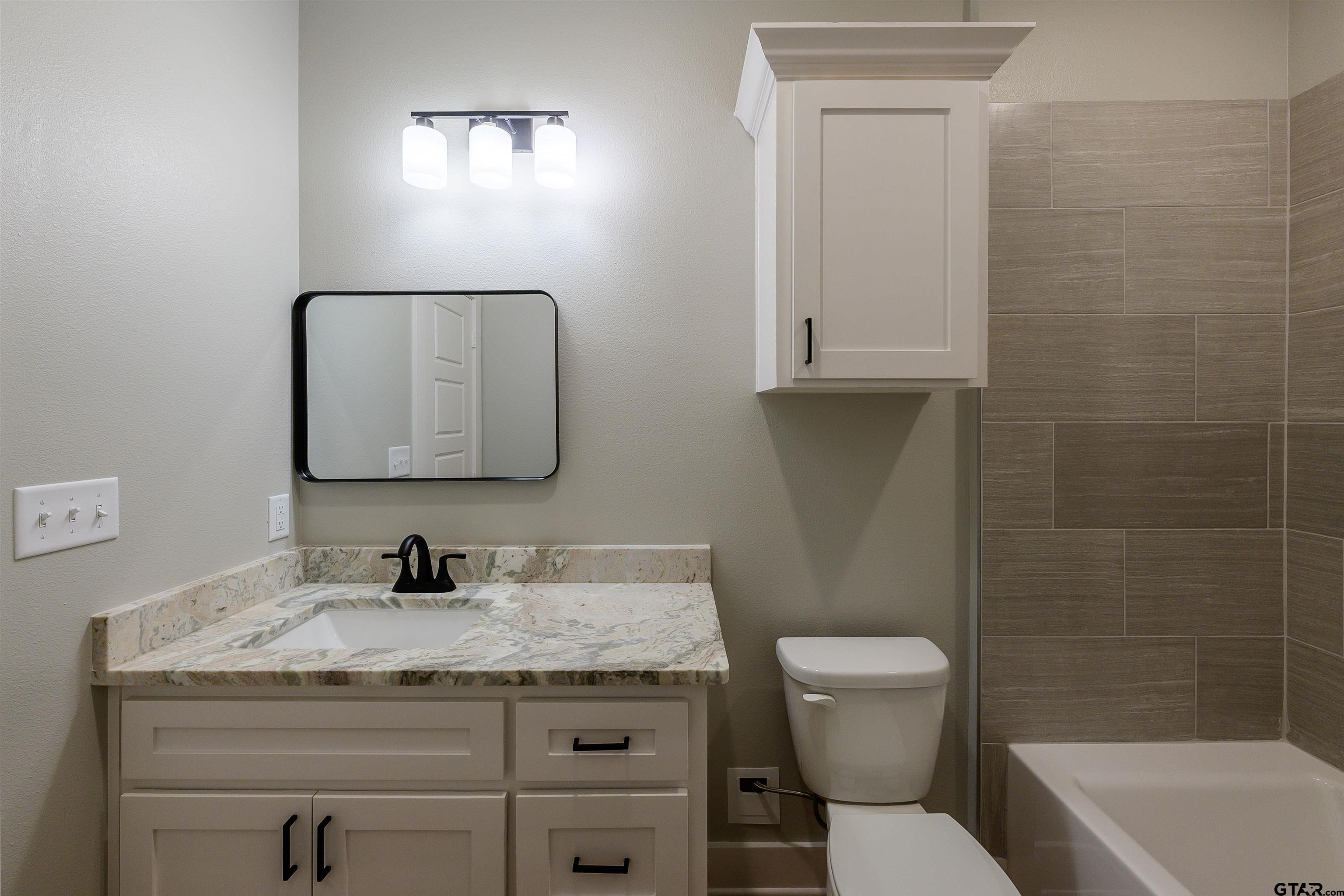 148 Crescent Bullard, TX 75757 - Photo 35 of 40 a bathroom with a granite countertop toilet a sink and mirror