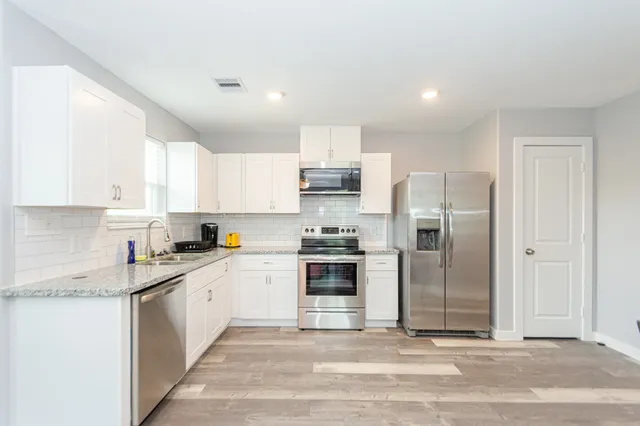 a kitchen with stainless steel appliances granite countertop a stove top oven a refrigerator and a sink