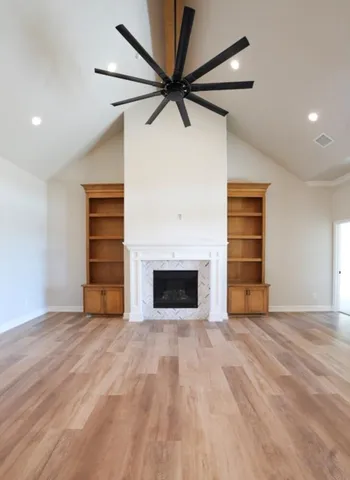 a view of an empty room with a fireplace and a ceiling fan