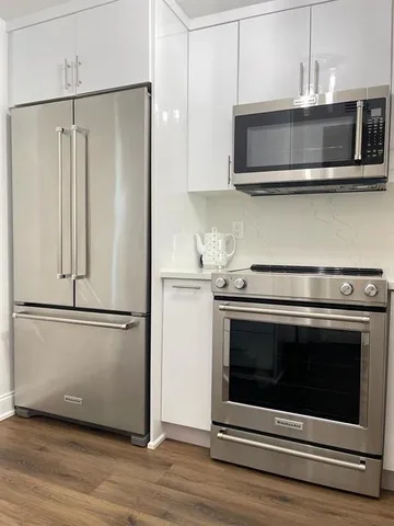 a kitchen with stainless steel appliances white cabinets and wooden floor