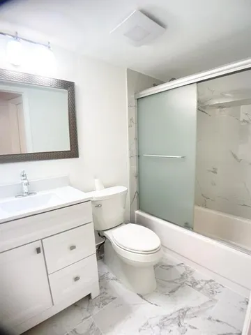 a bathroom with a granite countertop sink toilet a mirror and shower