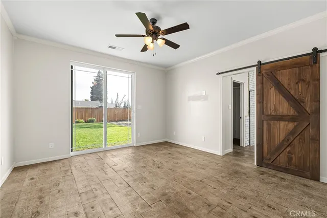 an empty room with ceiling fan and windows
