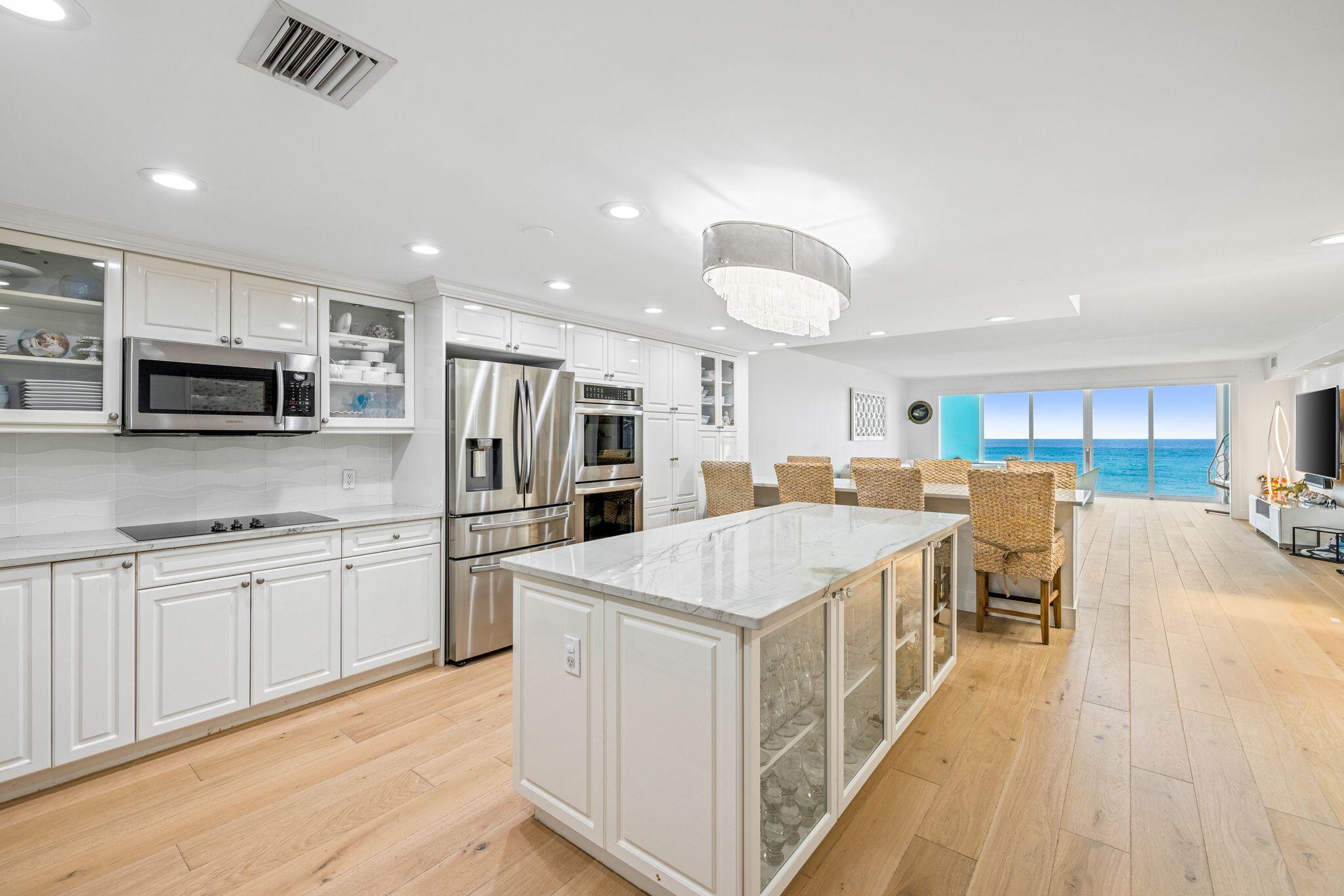 a large kitchen with stainless steel appliances kitchen island a stove a refrigerator a microwave oven a dining table and chairs with wooden floor
