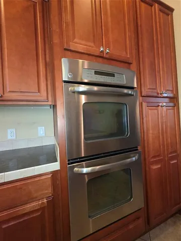 a large kitchen with kitchen island granite countertop a refrigerator a stove top oven a sink and a large window