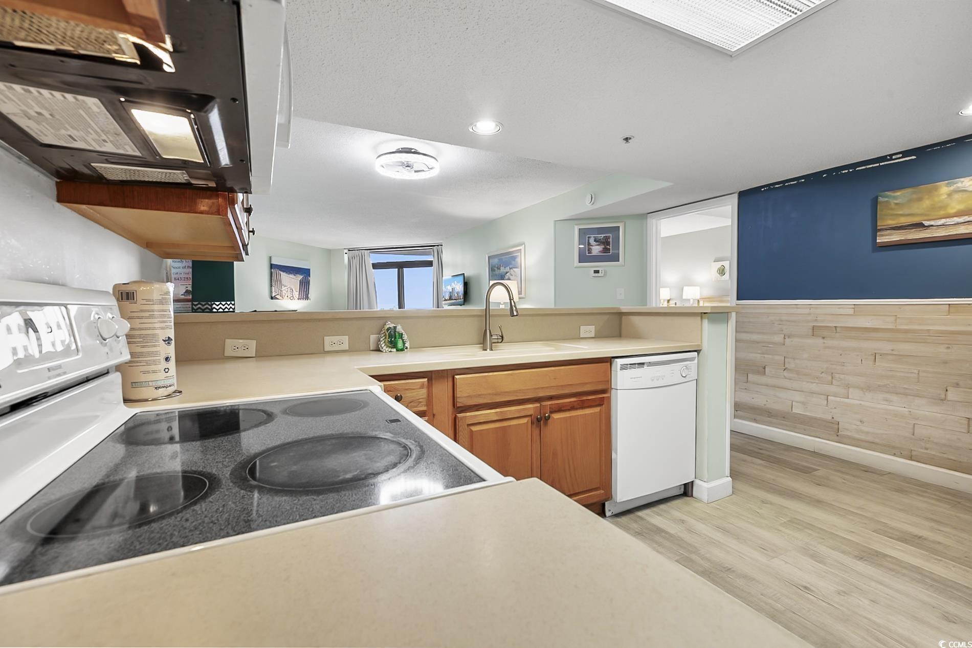 205 74th Avenue North, Unit 708 Myrtle Beach, SC 29572 - Photo 12 of 38 Kitchen with white appliances, wooden walls, light countertops, light wood-type flooring, and brown cabinetry