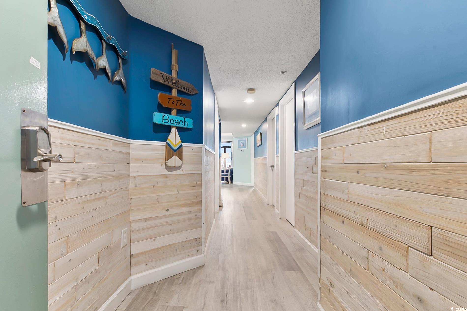 205 74th Avenue North, Unit 708 Myrtle Beach, SC 29572 - Photo 24 of 38 Corridor featuring wood finished floors, a textured ceiling, a wainscoted wall, and wooden walls
