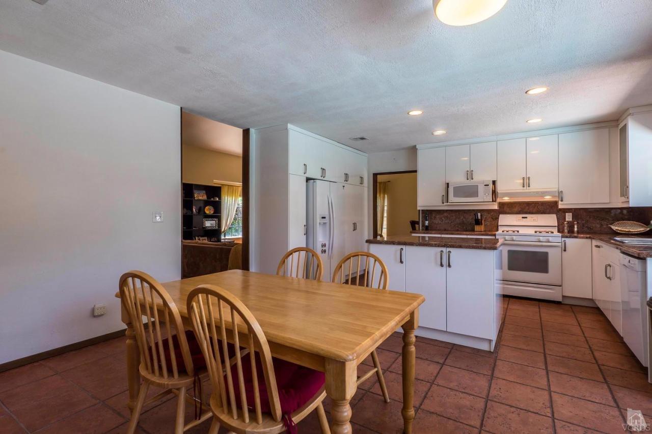 11529 East Buttercreek Road Moorpark, CA 93021 - Photo 11 of 36 a kitchen with stainless steel appliances kitchen island granite countertop a stove a sink a dining table and chairs