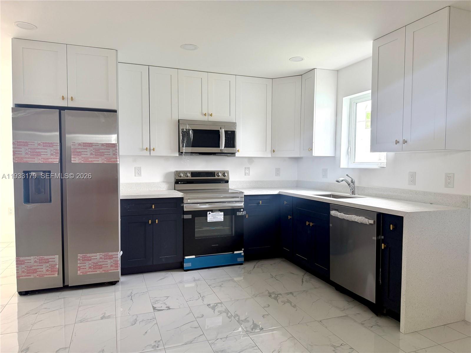 1629 Northwest 40th Street Miami, FL 33142 - Photo 3 of 17 a kitchen with stainless steel appliances granite countertop a refrigerator a stove a sink and a microwave