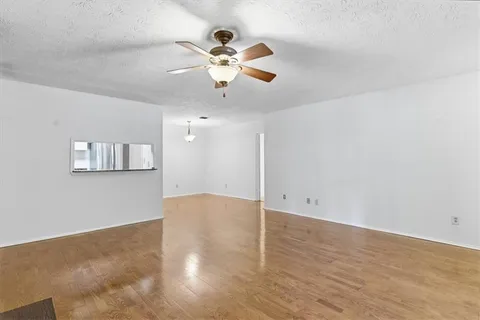 wooden floor in an empty room with a chandelier fan