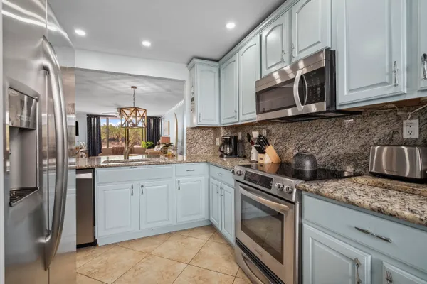 a kitchen with stainless steel appliances granite countertop a stove a sink and a microwave