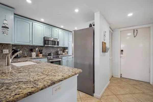 a kitchen with kitchen island granite countertop a refrigerator and a sink