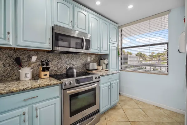 a kitchen with granite countertop white cabinets stainless steel appliances and a sink
