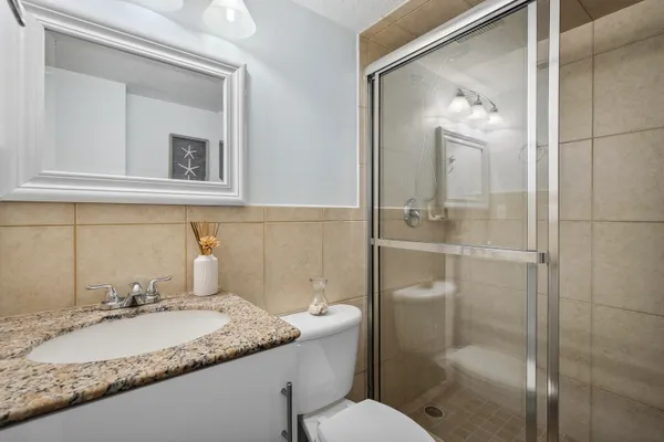 a bathroom with a granite countertop sink toilet and shower