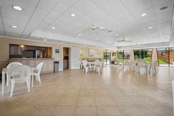 a dining hall with stainless steel appliances lots of white furniture a dining table and chairs