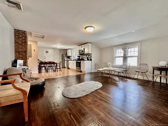 a living room with couches and kitchen view with wooden floor