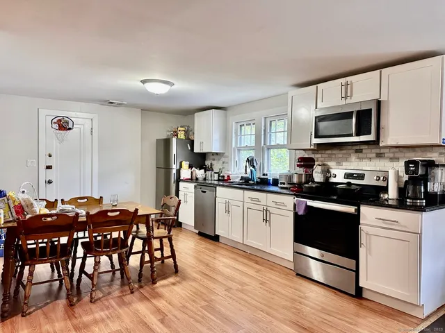 a kitchen with stainless steel appliances granite countertop a white cabinets and a stove top oven