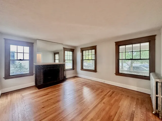an empty room with windows fireplace and wooden floor