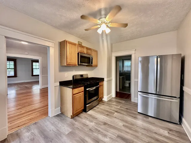 a kitchen with stainless steel appliances granite countertop a refrigerator a stove top oven a sink dishwasher and a refrigerator with wooden floor