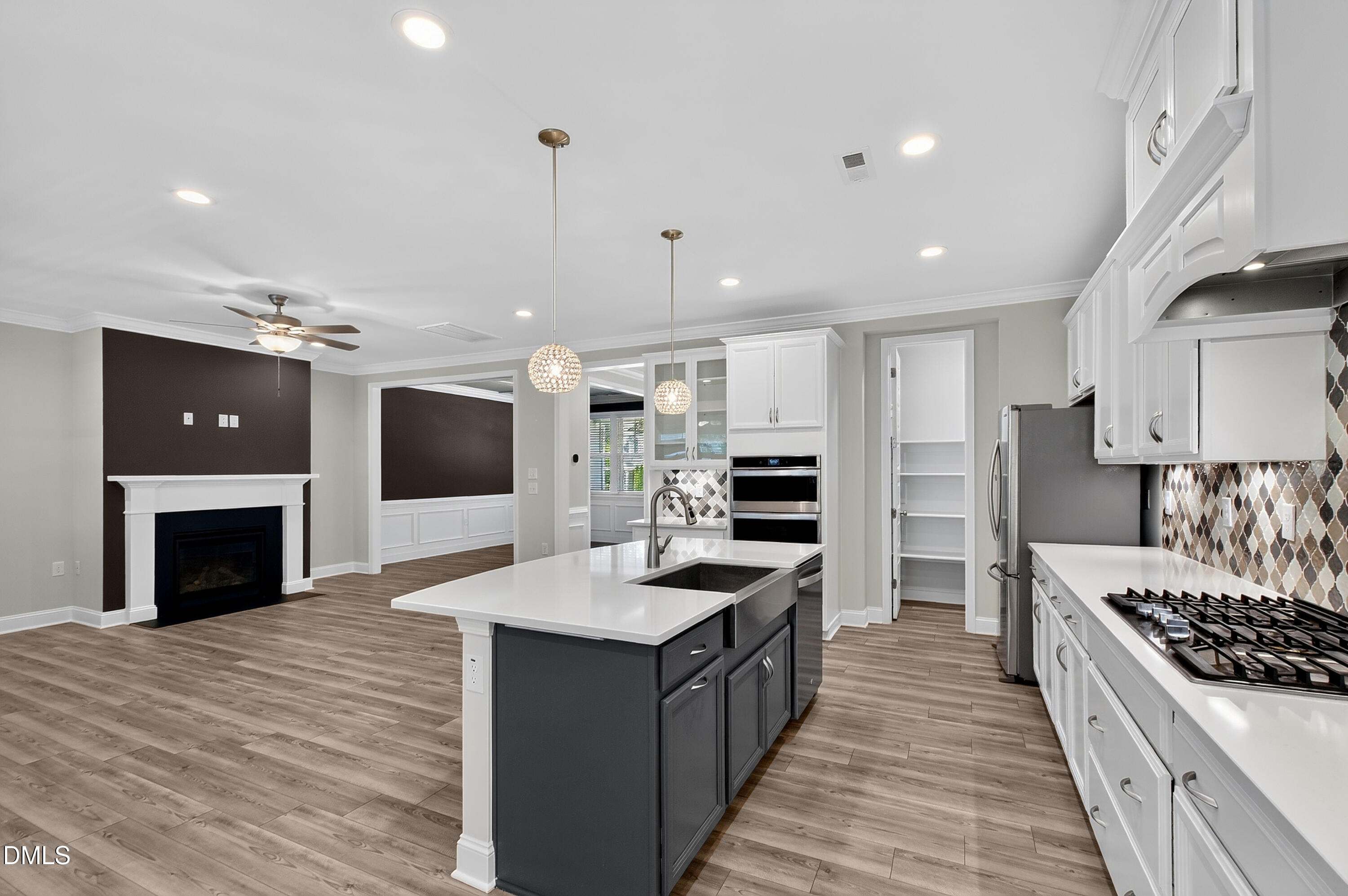 1300 Commons Ford Place Apex, NC 27539 - Photo 20 of 70 a large kitchen with stainless steel appliances kitchen island granite countertop a stove top oven a sink dishwasher a dining table and chairs with wooden floor