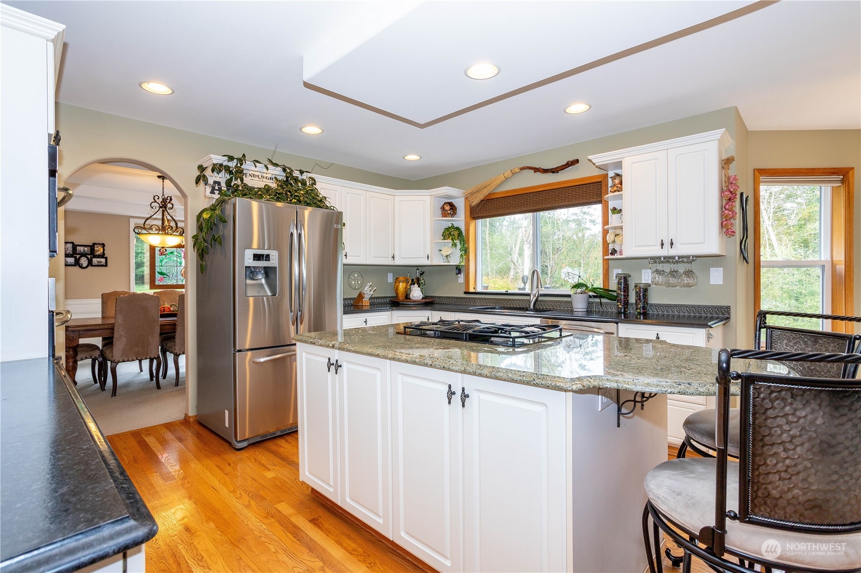 23408 Southeast 216th Way Maple Valley, WA 98038 - Photo 12 of 40 a kitchen with stainless steel appliances granite countertop a refrigerator a stove a sink and a dining table with wooden floor