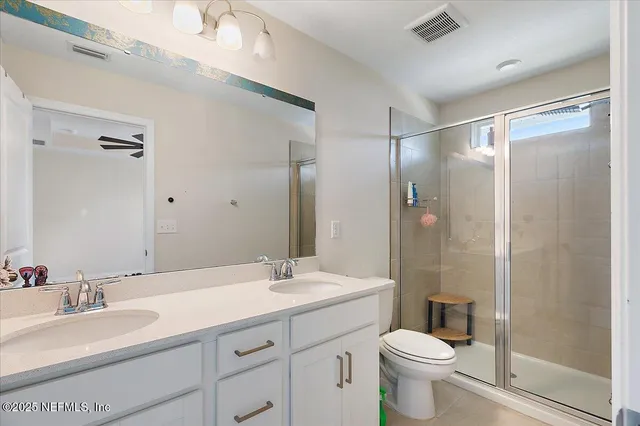 a bathroom with a double vanity sink toilet mirror and shower