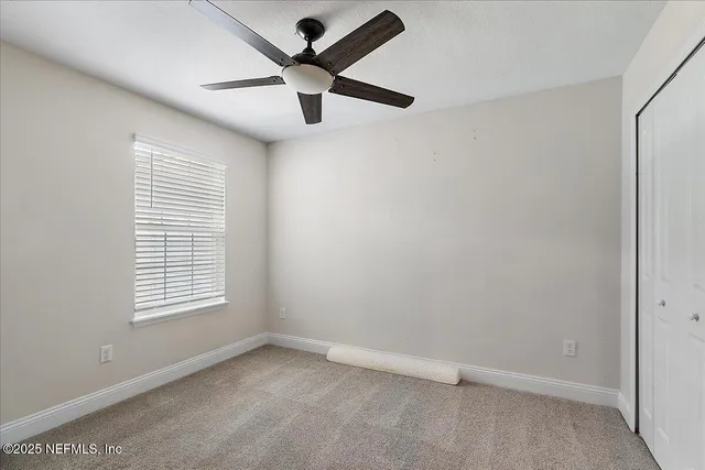 an empty room with window and ceiling fan