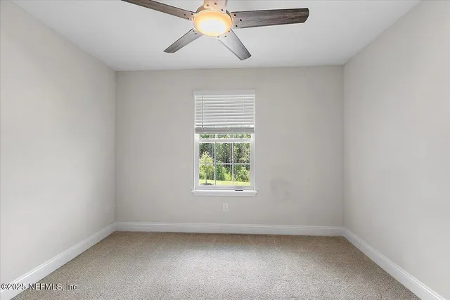 an empty room with a window and a fan