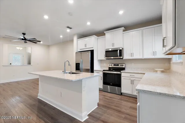 a kitchen with a sink stainless steel appliances and white cabinets