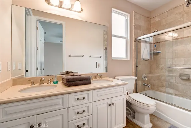 a bathroom with a double vanity sink toilet mirror and shower