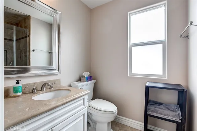 a bathroom with a granite countertop sink toilet and mirror