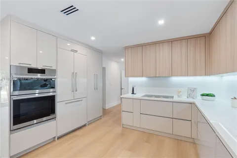 a kitchen with stainless steel appliances kitchen island granite countertop a stove a sink and white cabinets with wooden floor