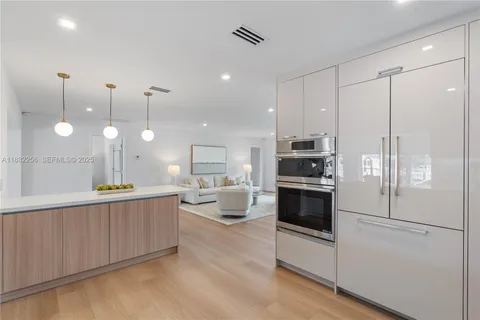 a large white kitchen with a large window and stainless steel appliances