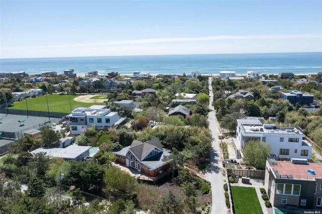 an aerial view of a city with lots of residential buildings and ocean view in back