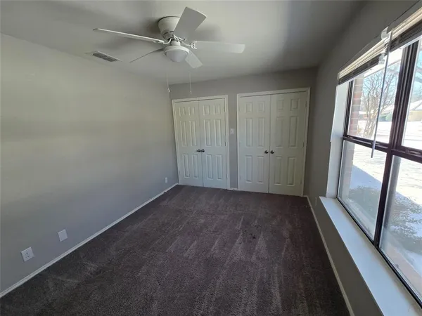 an empty room with windows and fan