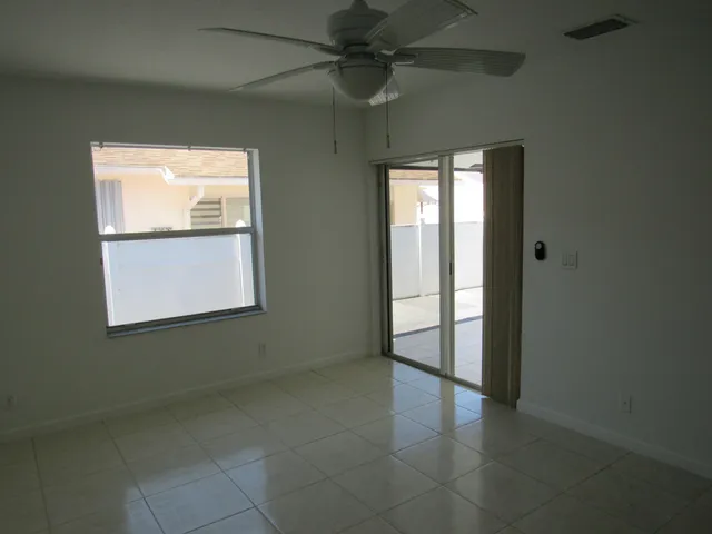 a view of an empty room with window and chandelier fan