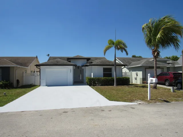 a palm tree sitting in front of a house with a yard