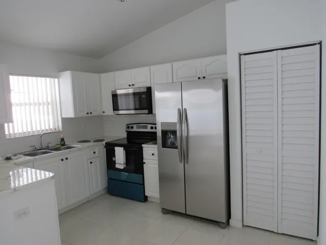 a kitchen with granite countertop a refrigerator and a stove top oven